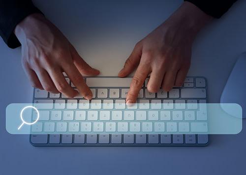 Person typing on a keyboard with a transparent search bar over the keyboard